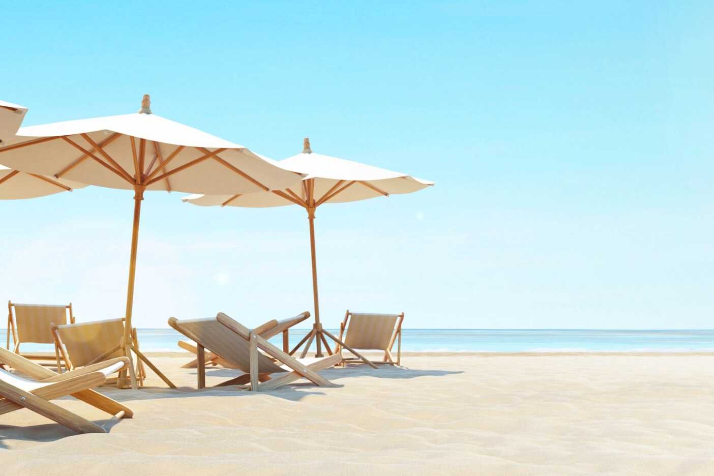 A serene beach scene with several deck chairs and large umbrellas positioned on sandy shores. The ocean is calm with a clear blue sky above, creating a peaceful and inviting atmosphere for relaxation. Nearby, you might find some of the best hair salons Cary NC has to offer for an extra touch of pampering.